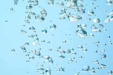 Many water bubbles on light blue background, closeup