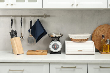 Retro mechanical kitchen scale and other utensils on white countertop indoors