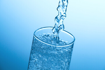 Pouring soda water into glass on light blue background, closeup