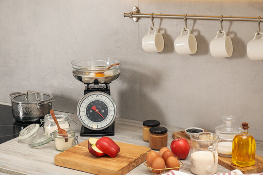 Retro mechanical kitchen scale and different food products on wooden countertop indoors