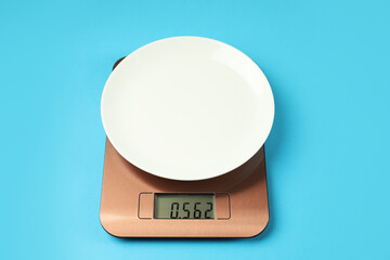 Electronic kitchen scale with plate on light blue background