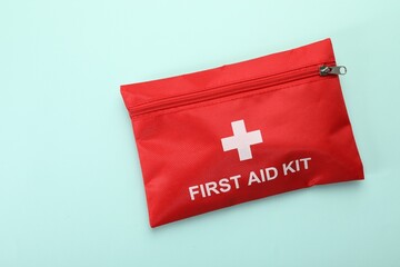 First aid kit on light blue background, top view. Space for text