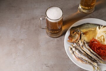 Different dried fish snacks and beer on grey table, above view. Space for text