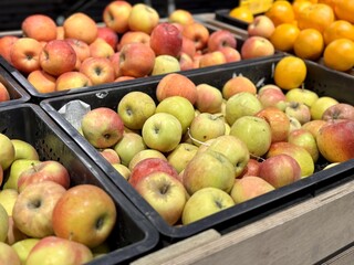 A mound of large red yellow coloured apples in boxes is displayed in the window of the supermarket's vegetable stand, demonstrating organic, vegetarian and healthy food. Close-up