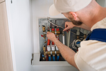 Plumber inspecting pipes in a heating system within a residential boiler room
