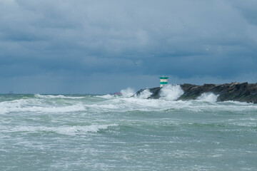 View on a pier and a lighthouse at the coast on a windy summer afternoon