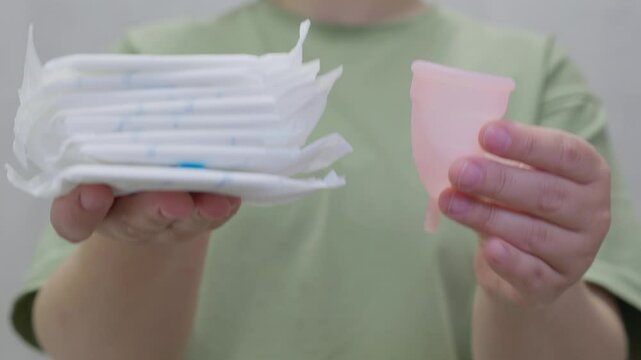 woman holding hygiene pad and menstrual cup making decision of hygienic products choosing. Different types of feminine menstrual hygiene materials 
