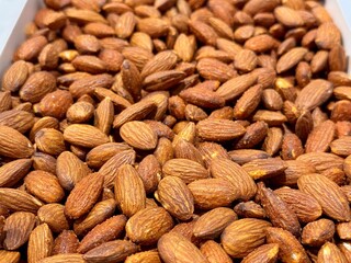 Delicious roasted almonds with spices are sold in large quantities at the vegetable market. Close-up