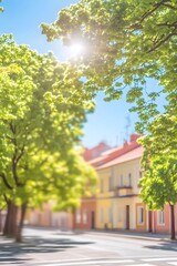 Obraz premium Sunny Street Scene with Lush Green Trees and Defocused Buildings