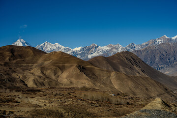 Arid Rolling Hills with Snow-Capped Himalayan Peaks in the Background Near Muktinath, Nepal