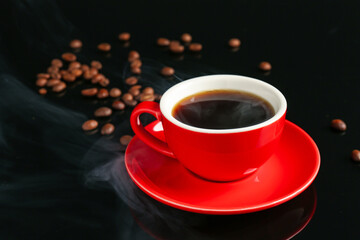 Red cup with coffee and roasted beans on black background