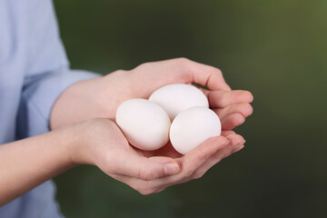 Woman with raw eggs on blurred background, closeup