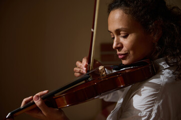 Woman deeply focused playing the violin in warm ambient lighting