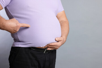 Overweight man in tight t-shirt on grey background, closeup. Space for text