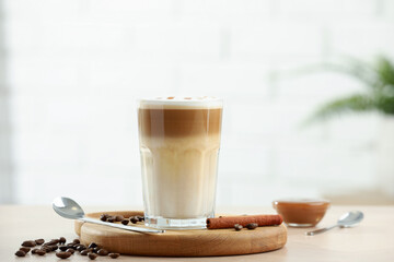Tasty latte macchiato in glass on wooden table