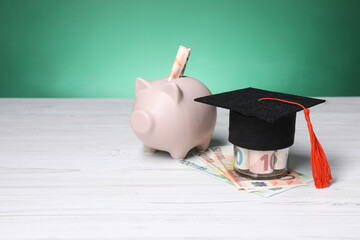 Graduate hat, euro banknotes and piggy bank on light wooden table, space for text. Tuition payment