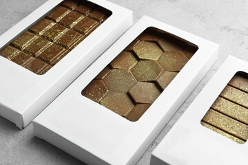 Tasty Dubai chocolate bars in packages with pistachios and knafeh on textured table, closeup. Space for text