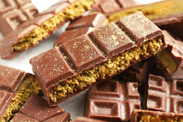 Pieces of tasty Dubai chocolate with pistachios and knafeh on white table, closeup