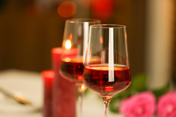 Romantic dinner. Glasses of red wine against blurred background, closeup. Space for text