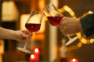 Couple clinking glasses of wine in restaurant, closeup. Romantic dinner