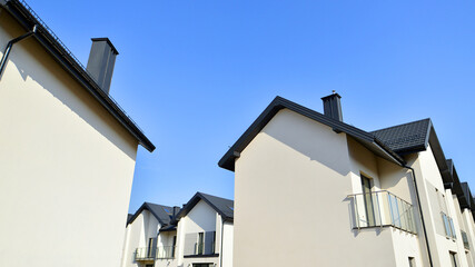 The real estate market in the suburbs. New single family houses in a new development area. Residential homes with modern facade. Terraced family homes in newly developed housing estate. 
