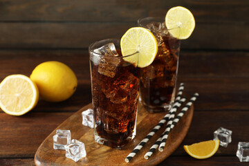 Fresh iced cola with lemon slices on wooden table, closeup