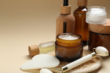 Different body care products and massaging tools on beige background, closeup. Space for text