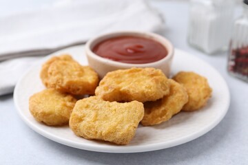 Tasty chicken nuggets with sauce on light table, closeup
