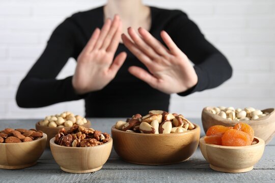 Woman refusing to eat products at grey wooden table, selective focus. Food allergy concept - Powered by Adobe