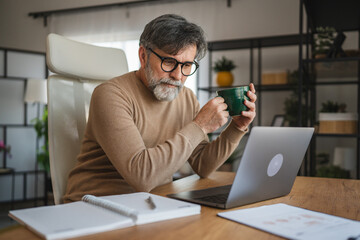 mature senior man relax from work and drink coffee at home office