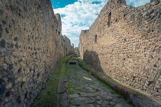 Stone-Paved Street Among Historic Ruins in Pompeii, Italy with Bright Sky