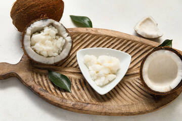 Wooden tray and bowl of natural coconut oil on white background, closeup