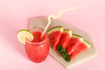 Glass of fresh watermelon juice with lime and mint on pink background