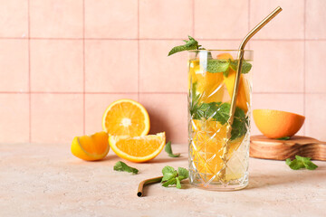 Glass of fresh lemonade with orange and mint on beige table