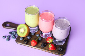 Glasses of fresh smoothie with different berries on lilac background