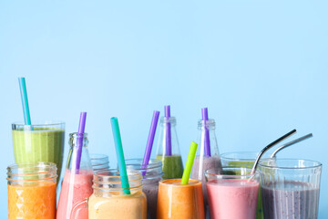 Glasses and bottles of different fresh smoothie on blue background