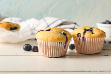 Tasty blueberry muffins on white wooden table, closeup