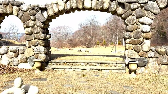 Discover the beauty of a rustic stone archway in a peaceful landscape.
