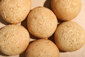 Fresh buns with sesame seeds on beige background, closeup