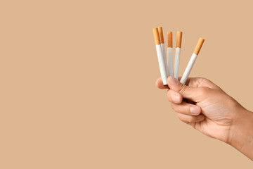 Female hand with cigarettes on beige background. Stop smoking concept