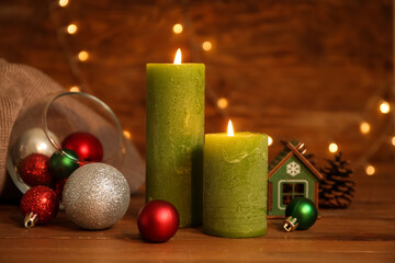 Burning candles and Christmas decor on table against wooden background with lights