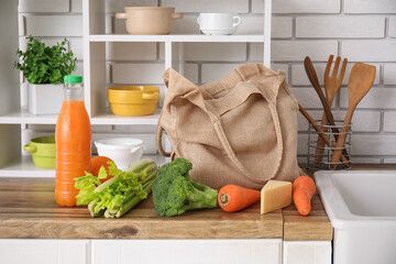 Eco bag with different fresh products on counter in kitchen
