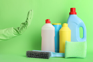 Hand of janitor and cleaning supplies on green background