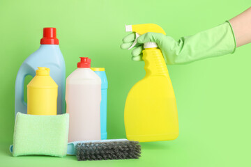 Hand of janitor and cleaning supplies on green background