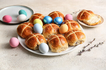 Plates with Easter cross buns, eggs and willow branches on white grunge background