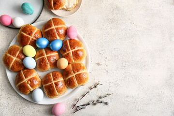 Plates with Easter cross buns, eggs and willow branches on white grunge background