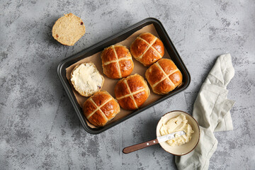 Baking tray with Easter cross buns and butter on grey grunge background