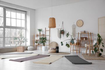 Interior of yoga studio with mats, plants and shelf units