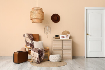 Interior of stylish living room with armchair, suitcase and commode