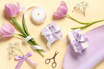 Gift boxes with flowers, wrapping paper and ribbon on light yellow background. International Women's Day